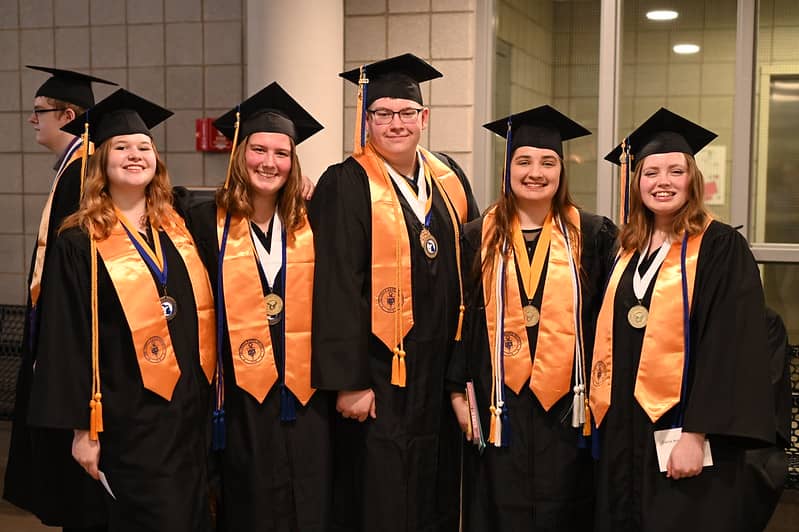Five graduates, smiling