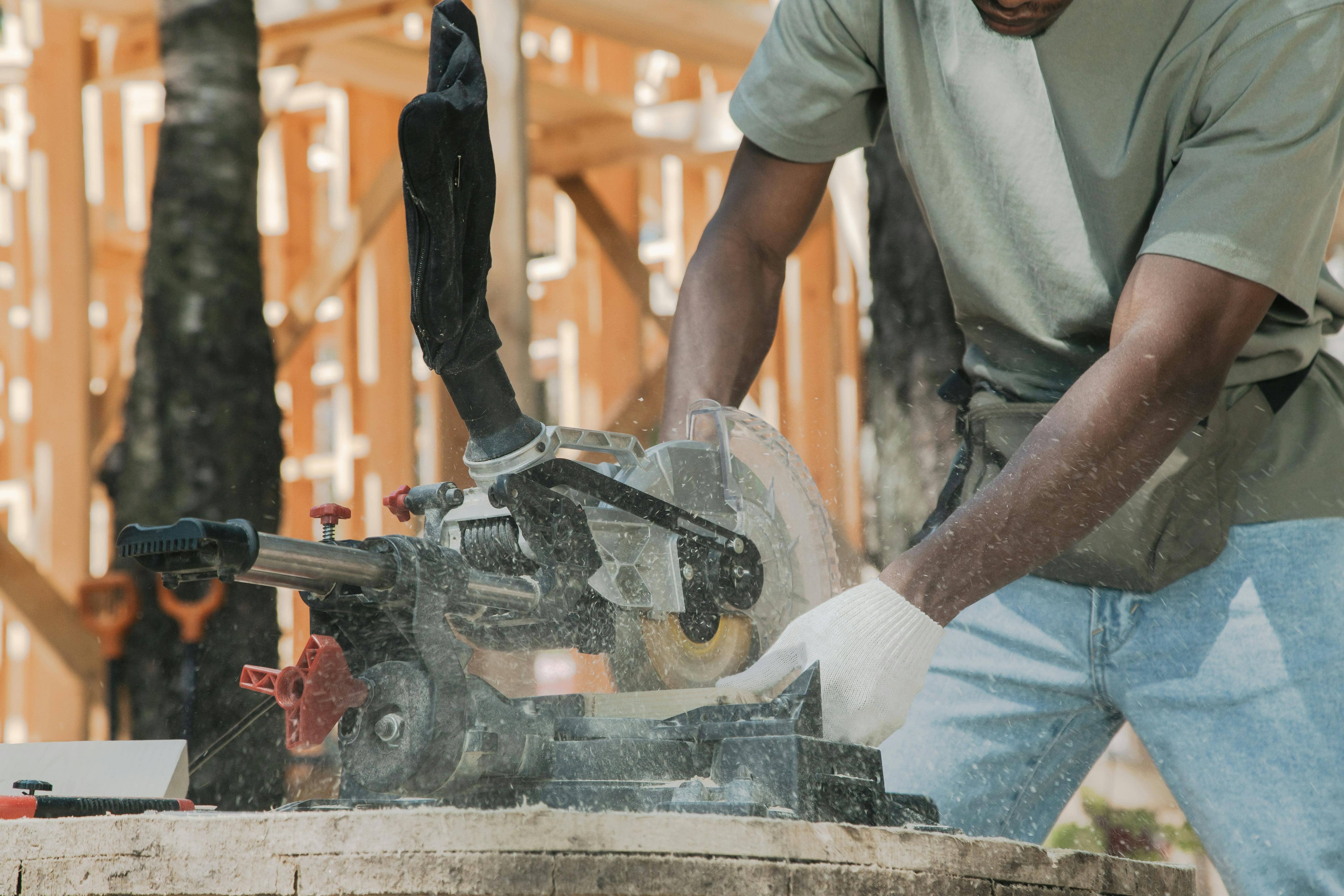 Person using a circular miter saw to cut wood at a construction site.