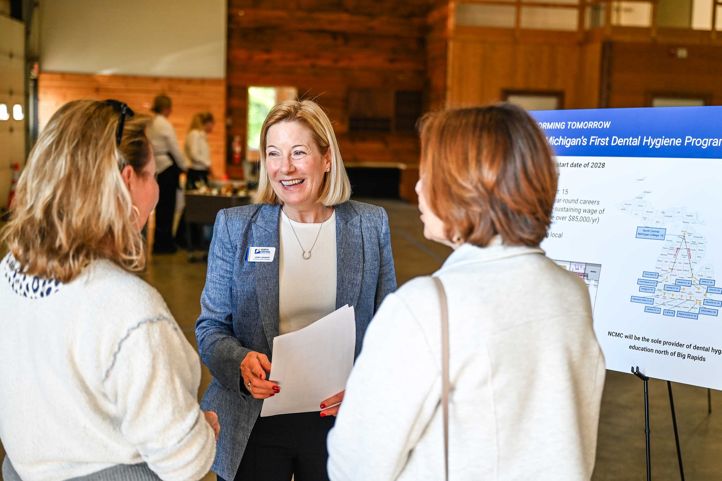 Jenny Johnson, NCMC Foundation Gift Officer, discusses floor plans with guests at the event held on June 18 in the new clinic site on Charlevoix Avenue in Bay Shore.