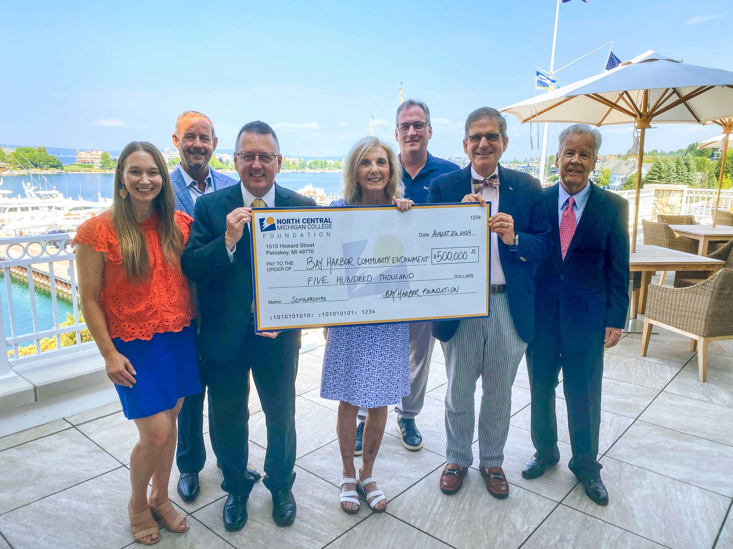 Seven individuals holding a large check, smiling