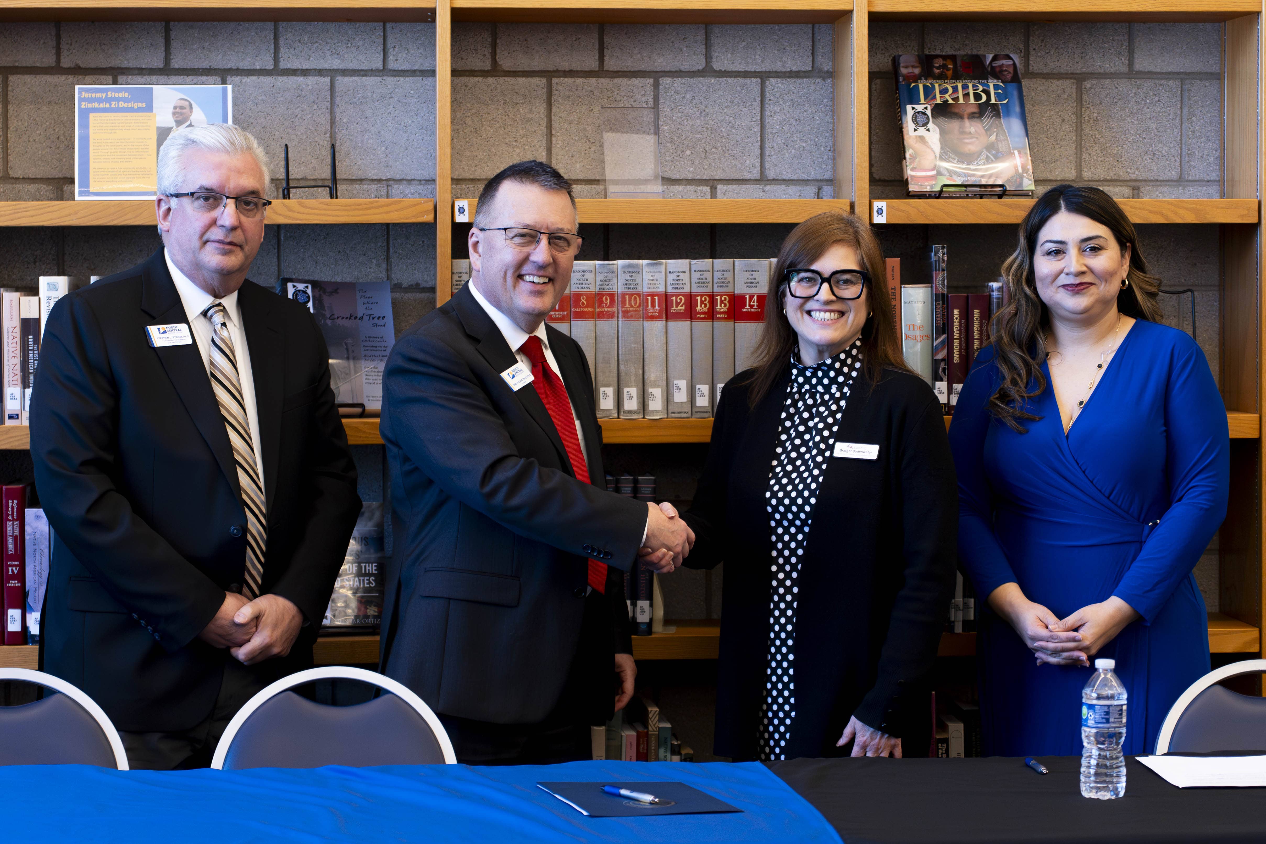 North Central Michigan College and Greater Michigan Construction Academy leaders shake hands during a partnership signing in the NCMC Library. From left: Stephen Strom, David Roland Finley, Bridget Sadenwater, and Cassandra Hernandez.